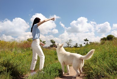 Teenage girl training her white Swiss Shepherd dog in field