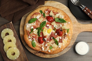 Pita pizza with prosciutto, pineapple, grilled tomatoes and egg on wooden table, flat lay