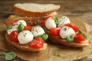 Delicious sandwiches with mozzarella, fresh tomatoes and basil on wooden table