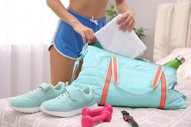 Woman packing sports stuff for training into bag at home, closeup