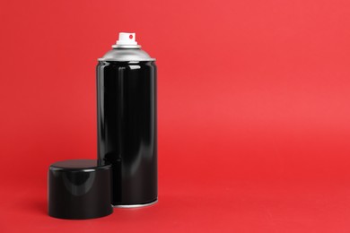 Black can of spray paint on red background. Space for text