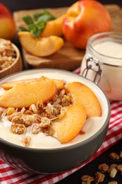 Tasty peach yogurt with granola and pieces of fruits in bowl on table