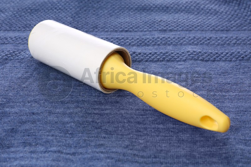 Photo of New lint roller with yellow handle on blue fabric