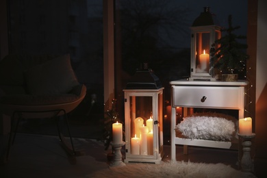 Photo of Beautiful lanterns with burning candles and Christmas decor in room. Interior design