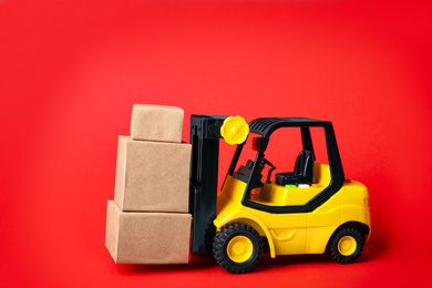 Toy forklift with boxes on red background Logistics and wholesale concept