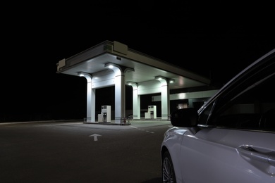 Photo of Modern car driving to gas station at night, closeup