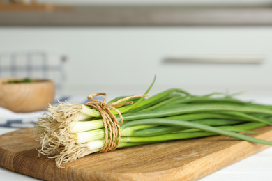 Fresh green spring onions on wooden board, closeup