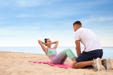 Couple doing exercise together on beach, space for text. Body training