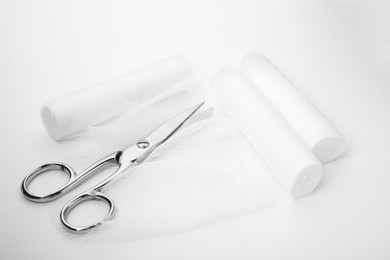 Medical bandage rolls and scissors on white background