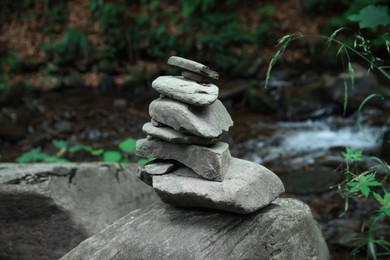 Many stacked stones near stream in forest