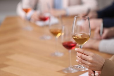 Sommeliers tasting different sorts of wine at table indoors, closeup