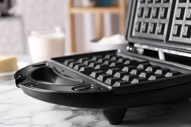 Photo of Modern Belgian waffle maker on white marble table, closeup