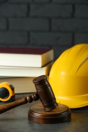 Photo of Construction and land law concepts. Judge gavel, construction helmet, tape measure and books on grey wooden table