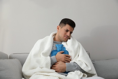 Ill man with hot water bottle suffering from cold at home