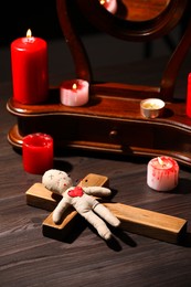Voodoo doll with pins in heart and ceremonial items on wooden table