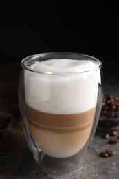 Delicious latte macchiato and coffee beans on grey table