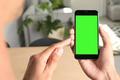 Image of Chroma key compositing. Man using smartphone with green screen indoors, closeup. Mockup for design
