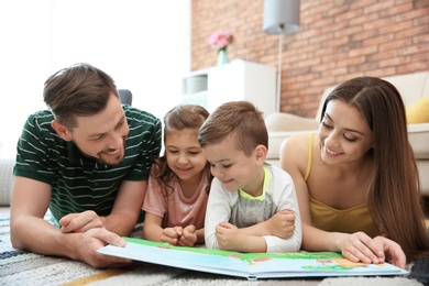 Young couple reading book with children at home. Happy family