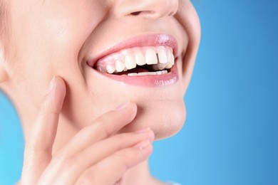 Woman with diastema between upper front teeth on light blue background, closeup