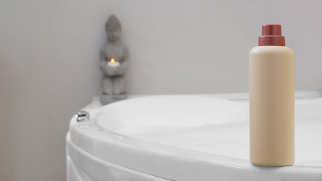 Beige bottle of bubble bath on tub indoors, space for text