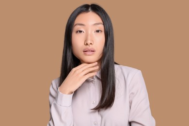 Photo of Portrait of beautiful young Asian woman in stylish outfit on beige background