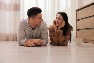 Happy couple lying on warm floor at home. Heating system