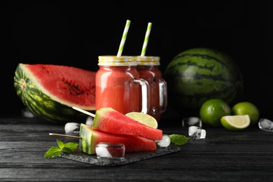 Slate board with juicy watermelon, ice and lime on black wooden table