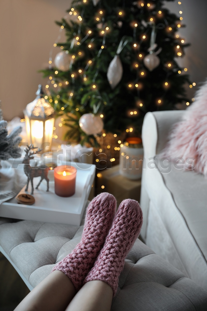 Woman wearing pink knitted socks in room decorated  for Christmas, closeup