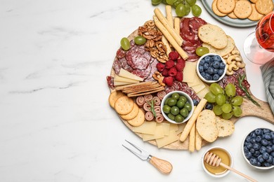 Tasty parmesan cheese and other different appetizers on white marble table, flat lay. Space for text