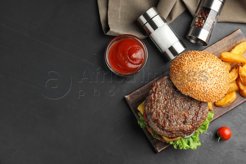Delicious burger with meat cutlet on black table, flat lay. Space for text