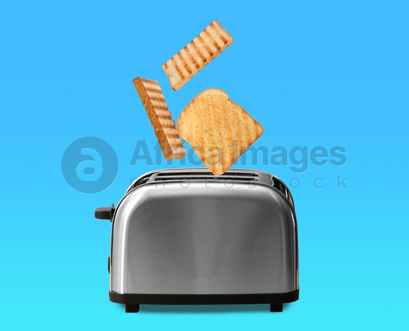 Slices of grilled wheat bread flying out of toaster on color background 