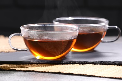Photo of Aromatic hot tea in glass cups on grey table, closeup