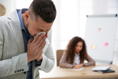 Sick man sneezing in office. Influenza virus