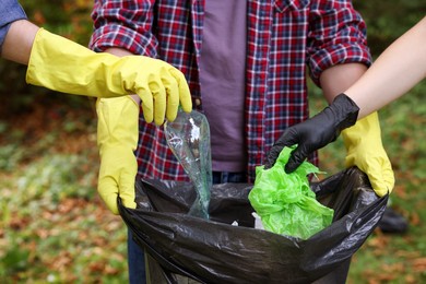 Photo of People with plastic bag collecting garbage in park, closeup