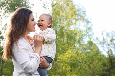 Happy mother with her cute baby in park on sunny day, space for text