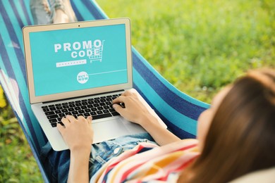 Woman with laptop activating promo code while doing online shopping outdoors