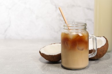 Photo of Mason jar of delicious iced coffee with coconut syrup on light grey table. Space for text