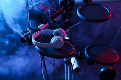 Modern electronic drum kit with headphones on dark background, color toned. Musical instrument