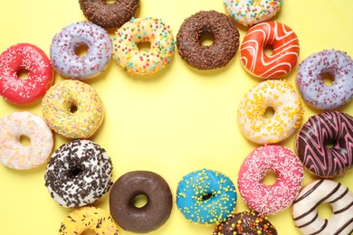 Photo of Delicious glazed donuts on yellow background, flat lay. Space for text