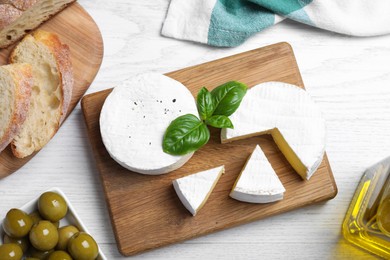 Flat lay composition with tasty brie cheese on white wooden table