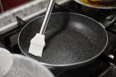 Photo of Greasing frying pan on stove in kitchen, closeup