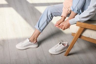 Woman rubbing sore foot at home, closeup