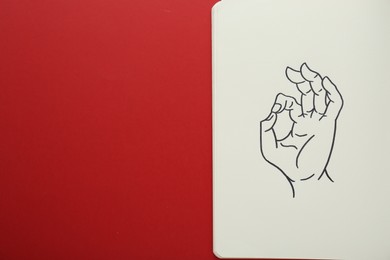 Photo of Notebook with drawing of hand showing okay gesture on red background, top view. Space for text