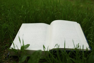 Open book on green grass in garden