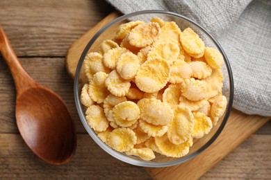 Photo of Bowl of tasty corn flakes on wooden table, flat lay