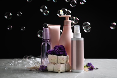 Set of hair cosmetic products, flowers and soap bubbles on black background
