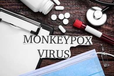 Photo of Flat lay composition with words Monkeypox Virus and medical supplies on wooden table