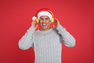 Happy man with headphones on red background. Christmas music