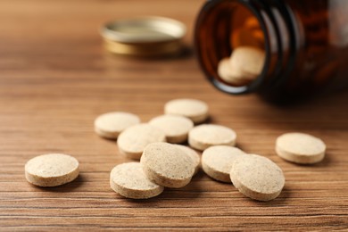Dietary supplement pills on wooden table, closeup
