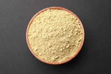 Wooden bowl with mustard powder on grey background, top view